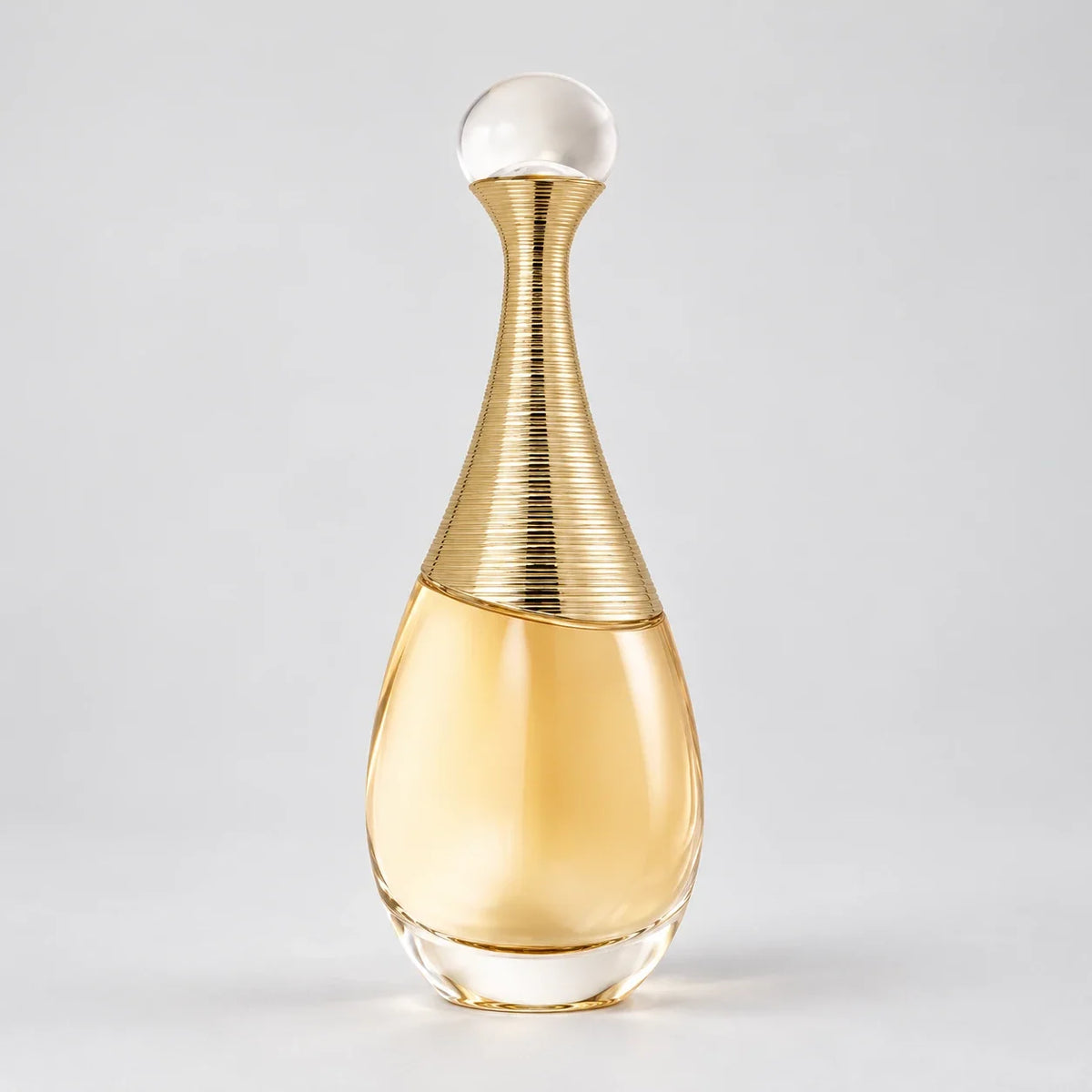 Dior J'adore Eau de Parfum gold perfume bottle on gray studio background